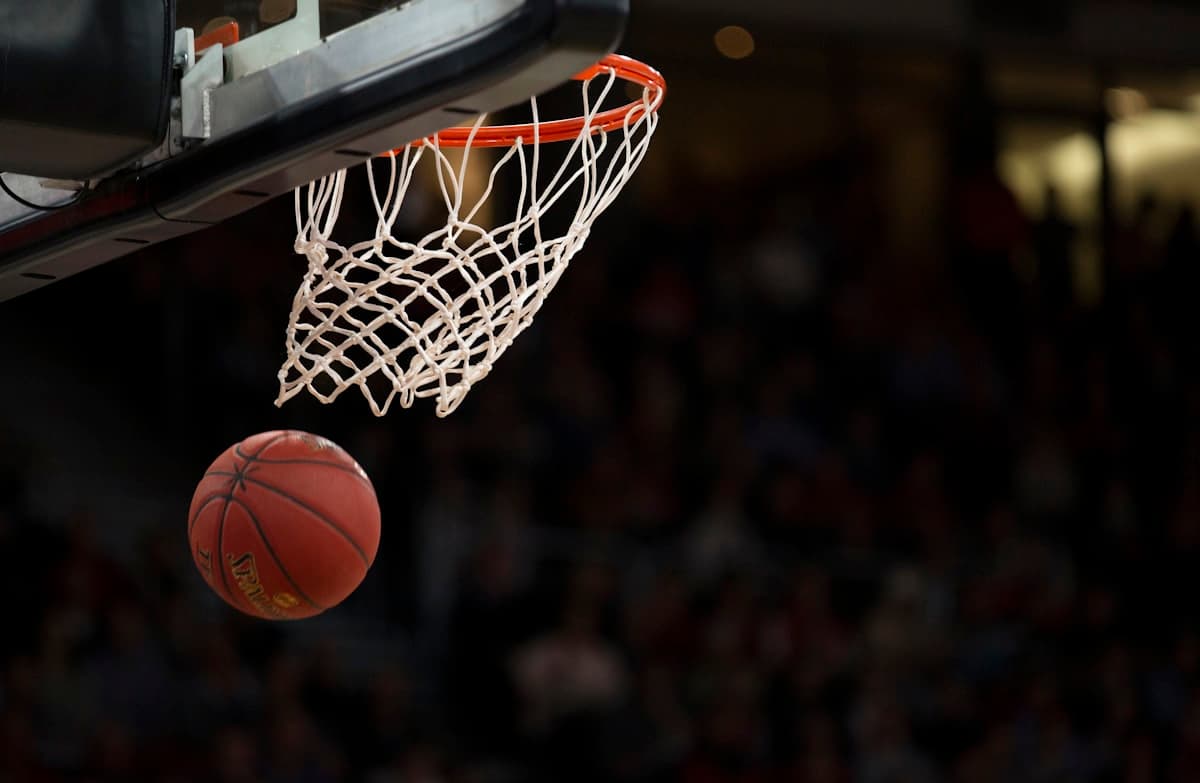 Basketball swishing through a hoop in an indoor arena