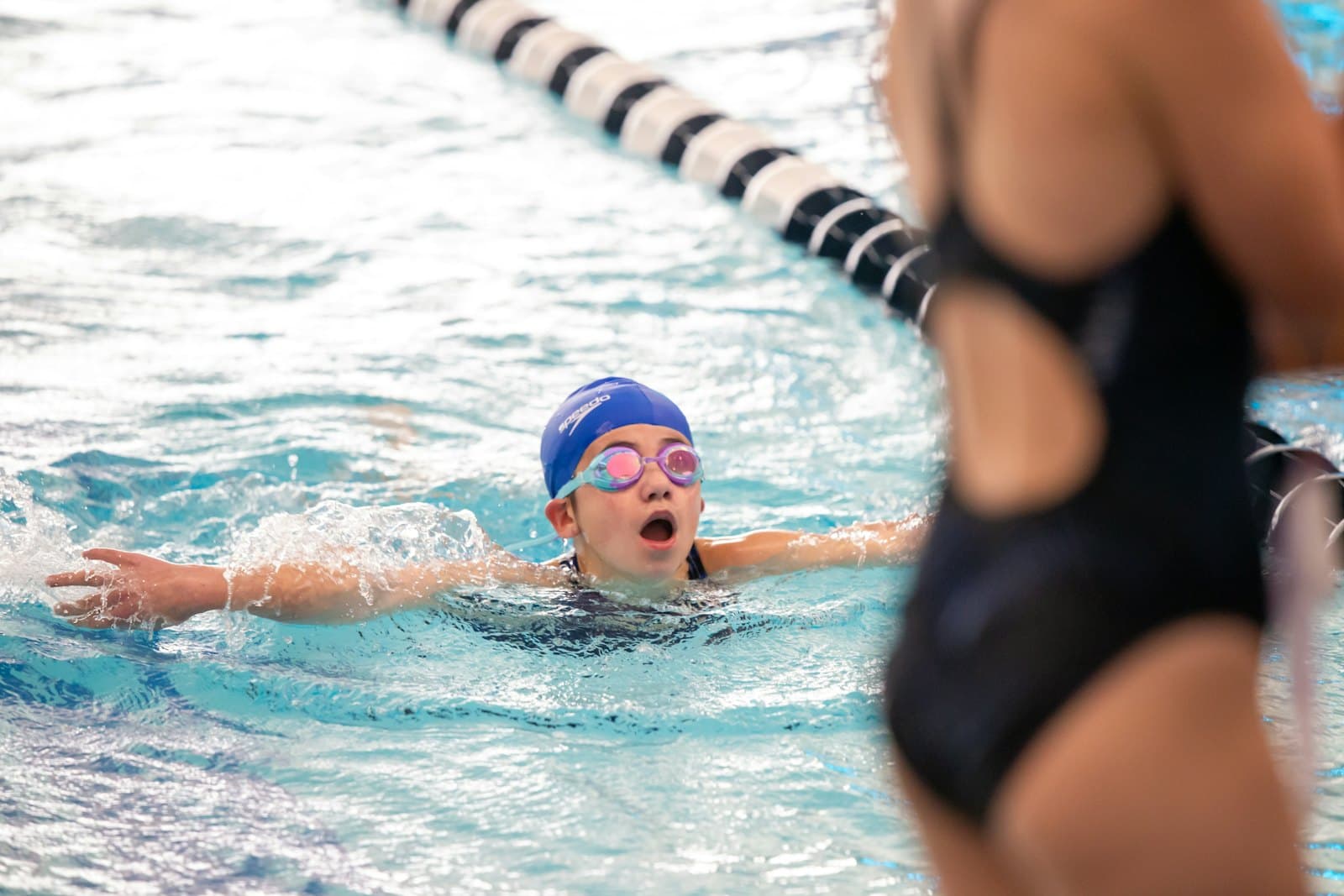 Young swimmer racing in a competitive pool lane during a swim meet for Swimming Nation