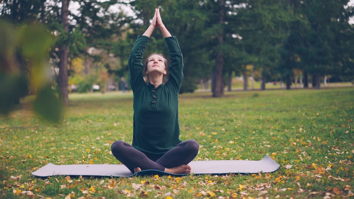 Young athlete in a calm outdoor yoga stretch — mindfulness, recovery, and wellbeing